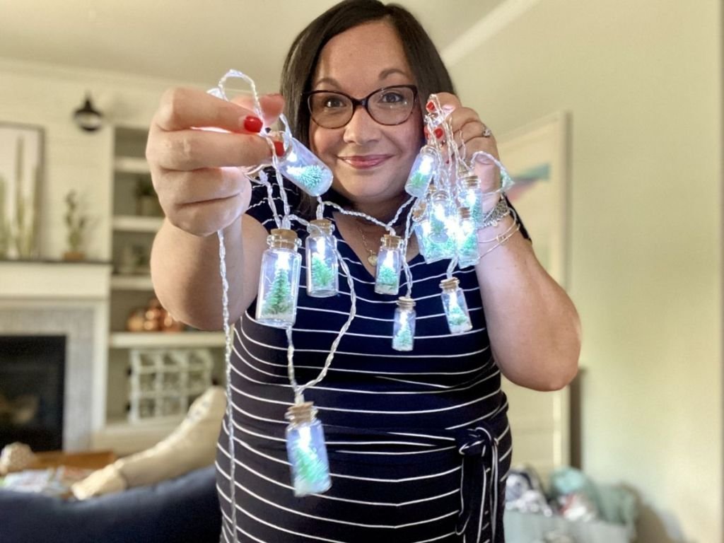 woman holding Christmas tree bottle string lights